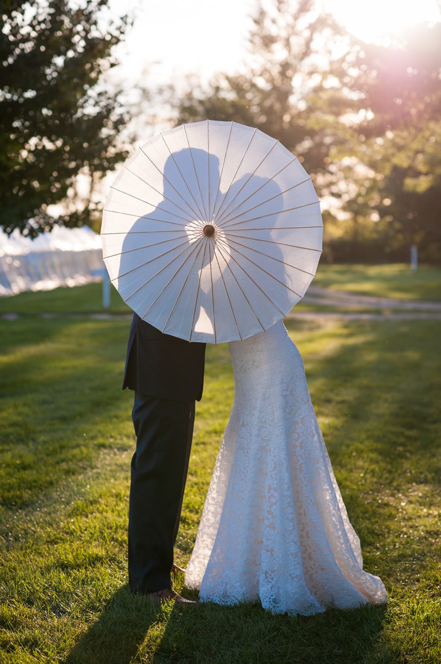 bride and groom kiss behind an umbrella {heritage prairie farm photo}
