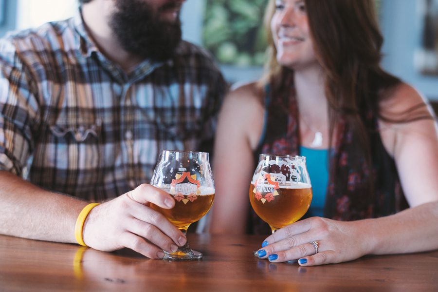 couple drinks beer at Penrose Brewing during their engagement session